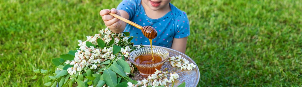 The child eats honey in the garden. Selective focus. Nature.