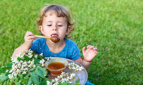 The child eats honey in the garden. Selective focus. Nature.