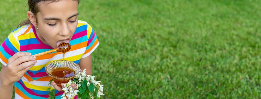 The child eats honey in the garden. Selective focus. Nature.