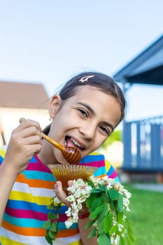 The child eats honey in the garden. Selective focus. Nature.