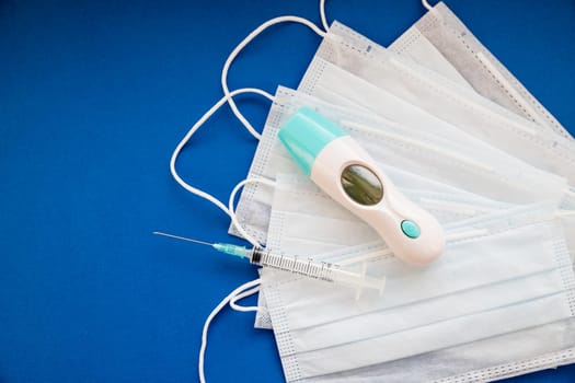 Medical protective mask syringe on a blue background. A typical 3-layer surgical mask for covering the mouth and nose.
