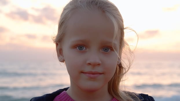 Horizontal photo of close-up of a 5-year-old blonde girl with blue eyes against the background of the evening sky