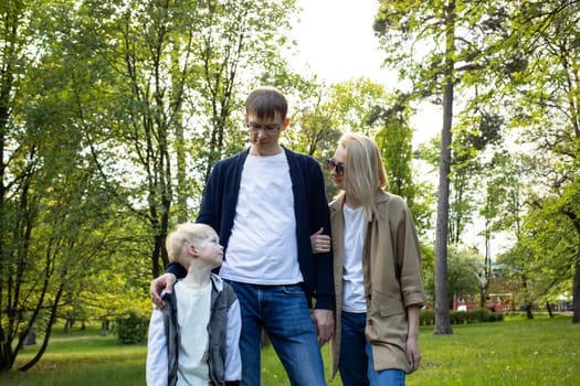 White Caucasian Family. Mother, Father, Little Boy Walk In Park, Enjoying Time Together. Summer Time. Happy Parenthood, Family Leisure Time. Love And Care. Horizontal Plane. High quality photo
