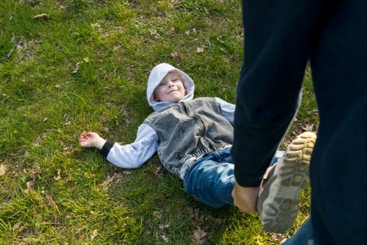 White Father Plays With Child In Meadow, Happy Smiling Boy Lying On Grass. Summer Time. Father's Day, Family Leisure Time, Playing Games. Emotional Connection, Love And Care. Horizontal Plane.