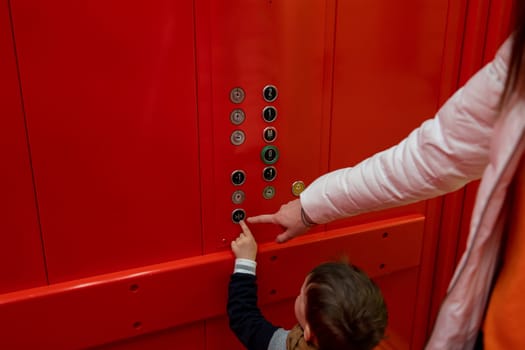 small boy pressing button in red elevator. High quality photo