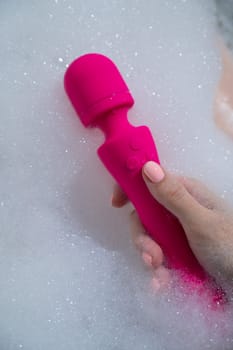 Woman lies in a bubble bath and uses a vibrator