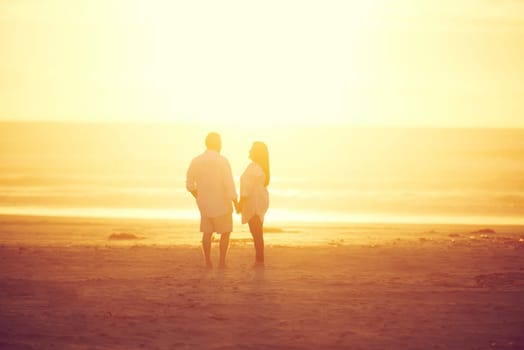 Keeping the romance alive. Rearview shot of an affectionate mature couple walking hand in hand on the beach