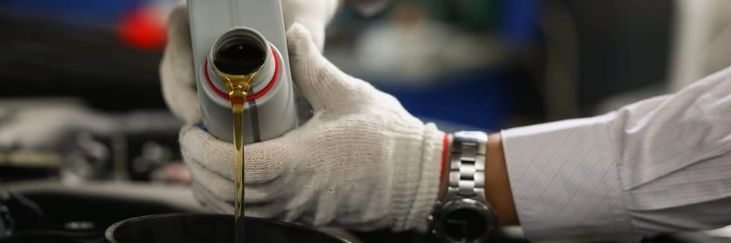 Hands of mechanic pours oil into car engine. Automotive quality oil in the engine concept
