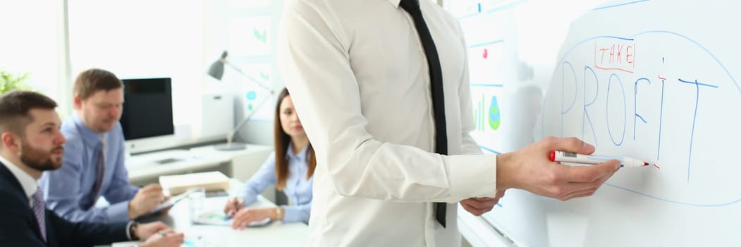 Confident business coach make presentation and profits in a business to group of workers. Team leader explaining chart on blackboard