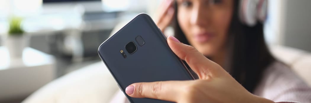 Woman in headphones holds smartphone. Applications for listening to music and learning concept