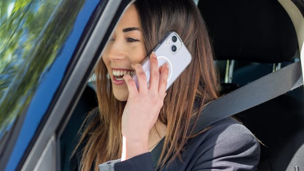 mixed asian race woman using cellphone, chatting on internet, working while driving in the city