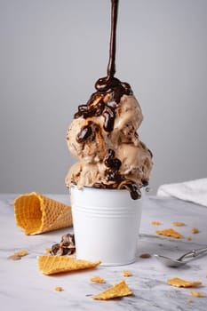 Chocolate ice cream with syrup in a white bucket.