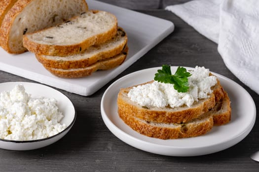 Sandwiches with cottage cheese and bread with olives on a gray table.