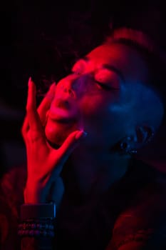 Sensual portrait of asian woman with short haircut smoking in neon light