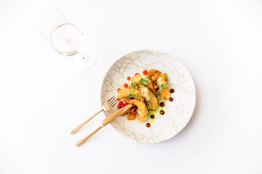 Exquisite serving of shrimps in batter on a brown plate on a white background