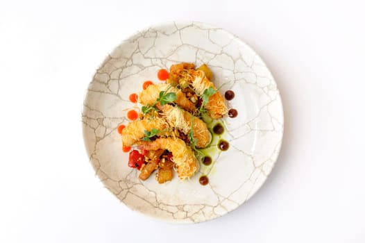 Exquisite serving of shrimps in batter on a grey plate on a white background