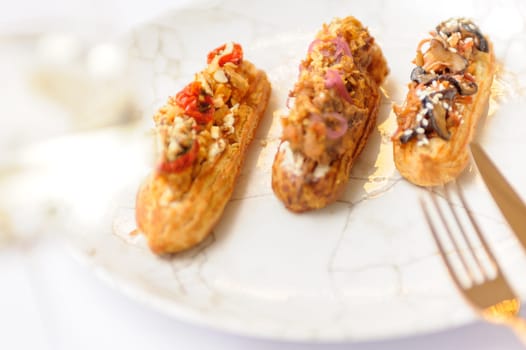 Eclairs with various fillings on a gray plate close up