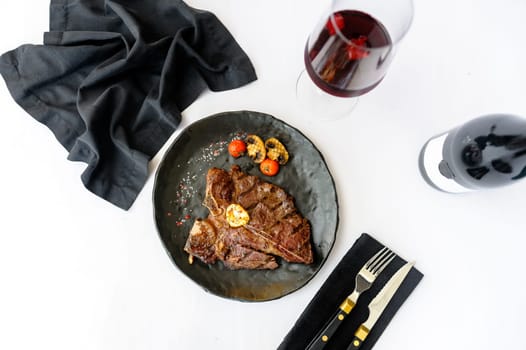 Exquisite serving of bone-in beef steak on a black plate on a white background