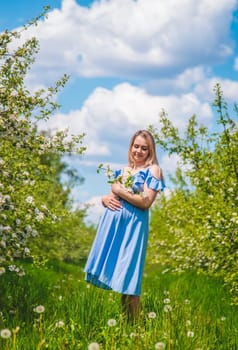 Pregnant woman in the garden of flowering apple trees. Selective focus. Nature.