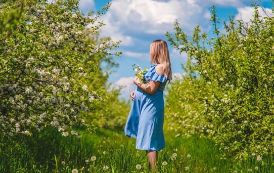 Pregnant woman in the garden of flowering apple trees. Selective focus. Nature.