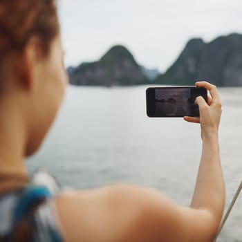 Something to look back on and smile. a young woman taking pictures of a river in Vietnam with her smartphone