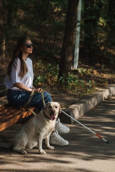 Blind caucasian woman sitting on bench with guide dog
