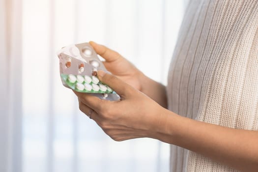 Hand holding a blister pack of medicine pill on blurred white curtain  background for medical and healthcare concept