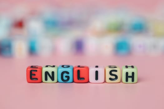 The word ENGLISH from letter beads on pink background for education and learning concept, selective focus image