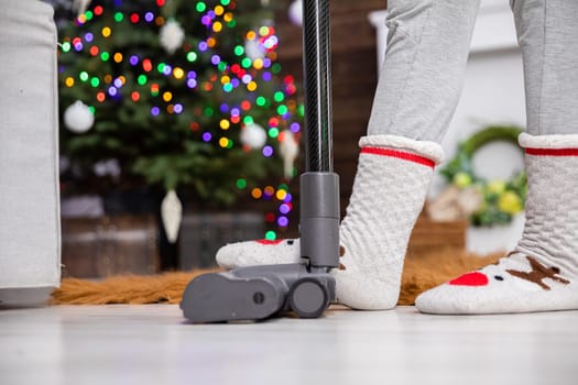 Suction tip from a vacuum cleaner pressed with a foot. Christmas cleaning in the living room. Second plan in blur e bokeh effect.