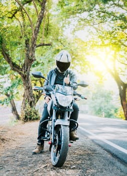 Motorcyclist in safety helmet with thumb up on the road. Biker wearing safety helmet with thumb up on the road