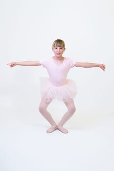 Little ballerina dancer in a pink tutu academy student posing on white background.