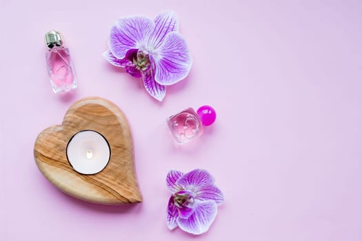 Beauty blog concept. Accessories, flowers, cosmetics and candle on pink background, copyspace.