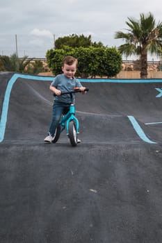 A young child rides the new South Glenmore Park BMX pump track on his bike on a summer evening in Calgary Alberta Canada.