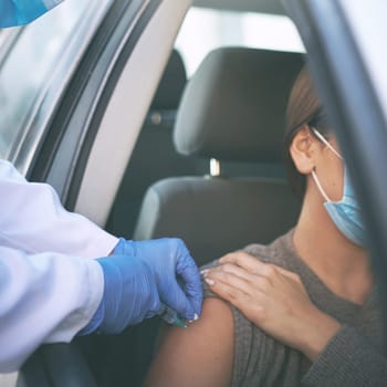 Arm yourself with proection. a masked woman receiving an injection at a Covid-19 drive through testing centre