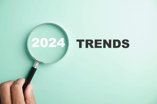 The image features magnifier glasses with the text New Year 2024 Trends, emphasizing the main trend of change. It represents the evaluation methods, popular topics, and new trends in business.