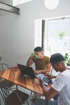 Fuel up and get back to the grind. two handsome friends sitting together and using technology in a coffeeshop