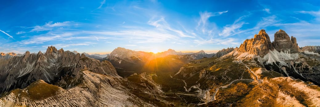 Rocky mountains rise above deep canyons. Mountain landscapes of primeval nature under blue sky. Tre Cime di Lavaredo at sunset aerial view