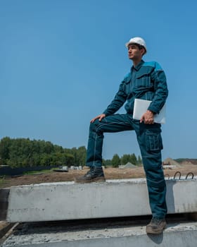 Caucasian male builder in hardhat holding laptop at construction site