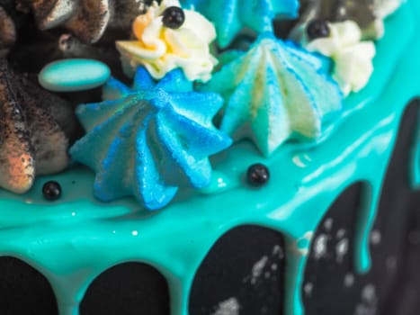 frosted black painted cup cake with blue turquoise dripping and colored handmade meringue topping studio white isolated background