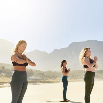 Gain a sense of inner calm. three young women practicing yoga on the beach