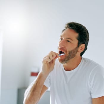 Fresh breath, fresh day. a handsome middle aged man brushing his teeth in the bathroom at home