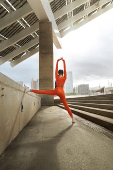 Young athlete stretching arms and legs after exercising. Woman workout in the city. Sports concept. Vertical image. Active lifestyle concept. Copy space.
