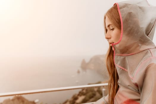 Woman rain park. Happy woman portrait wearing a raincoat with transparent umbrella outdoors on rainy day in park near sea. Girl on the nature on rainy overcast day