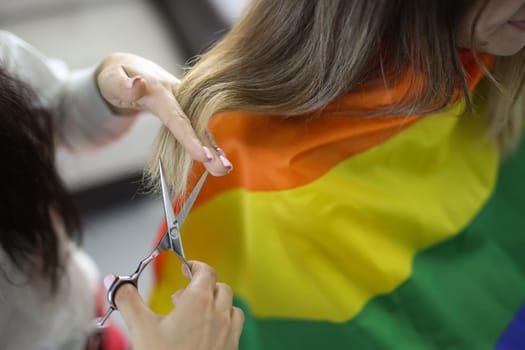 Hairdresser cuts split ends of woman hair with scissors. Barbershop for sexual minorities and LGBT community concept
