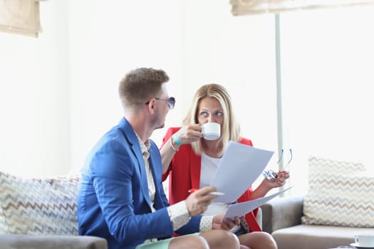 Young couple is chatting over cup of coffee in cafe and looking through business documents. Business meeting in cafe concept