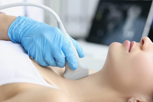 Adult woman undergoes ultrasound of thyroid gland in office of female doctor. Thyroid disease concept