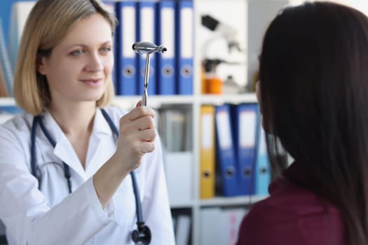 Female neurologist examines patient with hammer in private clinic. Neurologist consultation and diagnosis of diseases concept