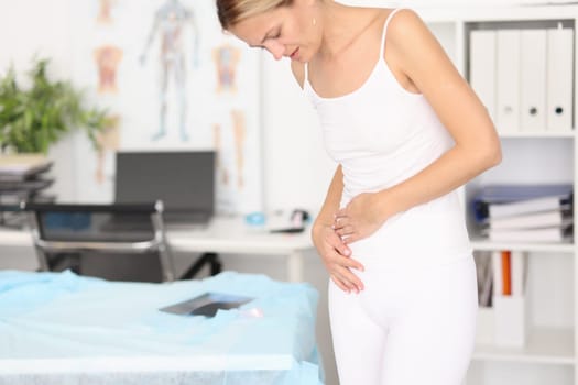 Woman with severe abdominal pain in clinic. Menstruation, gastritis abortion concept