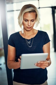 Technology that engages and empowers. a young businesswoman using a digital tablet in an office