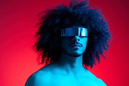 Portrait of fashion man with curly hair on red background with stylish glasses, multinational, colored light, black leather jacket trend, modern concept, sexy body. High quality photo